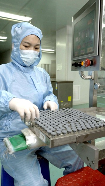 Operator holding a loaded vial tray at the line